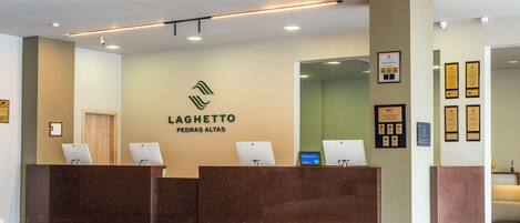 Una mesa de recepción con un logotipo, diplomas enmarcados y un monitor de computadora.