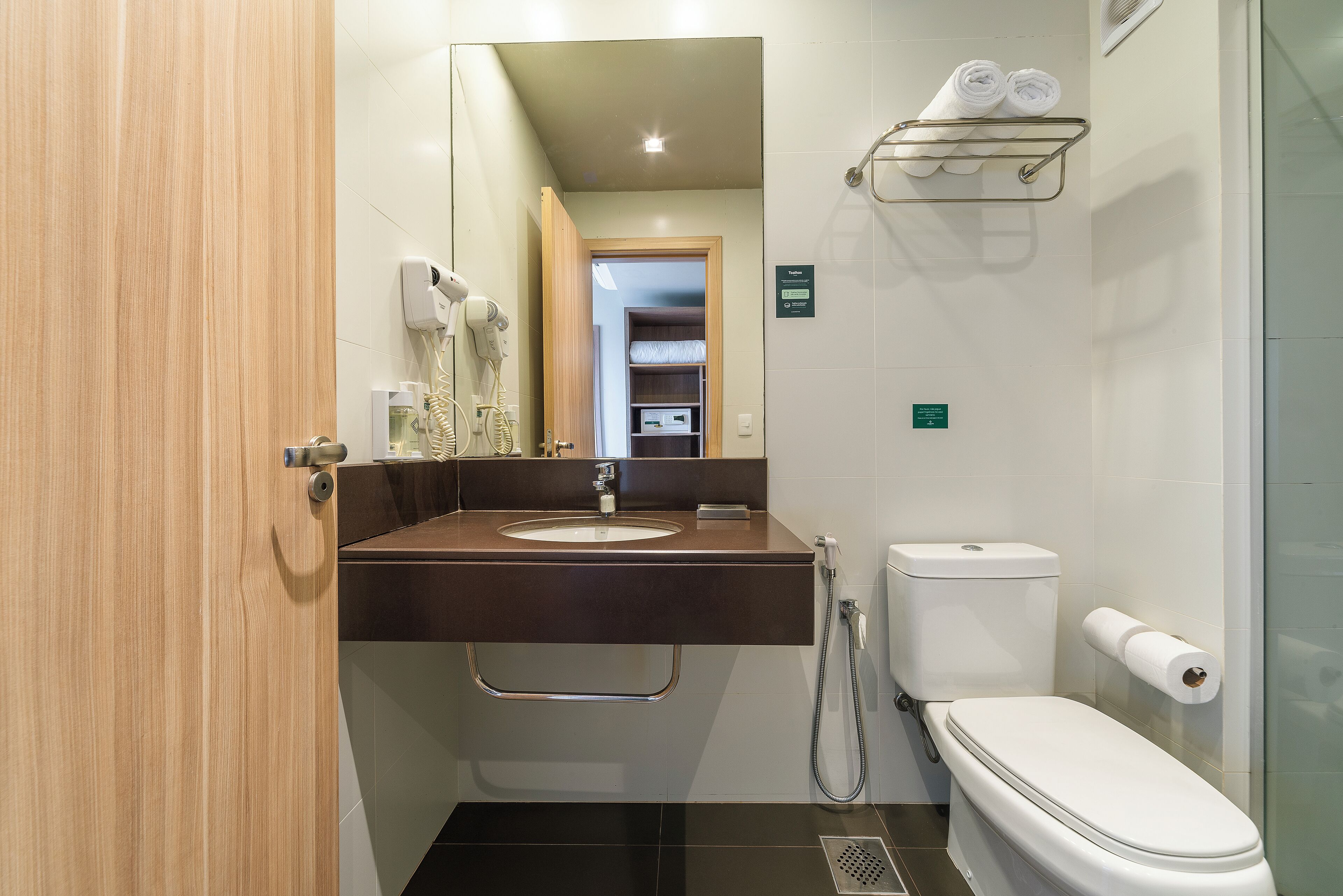 Un baño moderno con tocador de madera, inodoro y zona de ducha.