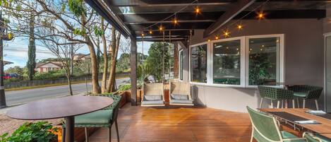 An outdoor patio with wooden flooring, green cushioned chairs, and a table.