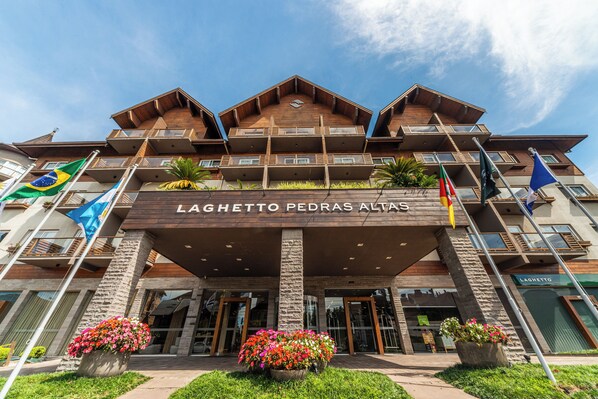 Un hotel amb una entrada destacada, diversos balcons i banderes.