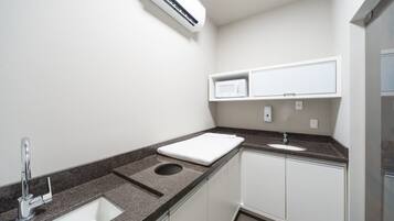 A compact bathroom with a sink, a mirror, a towel, and a microwave.