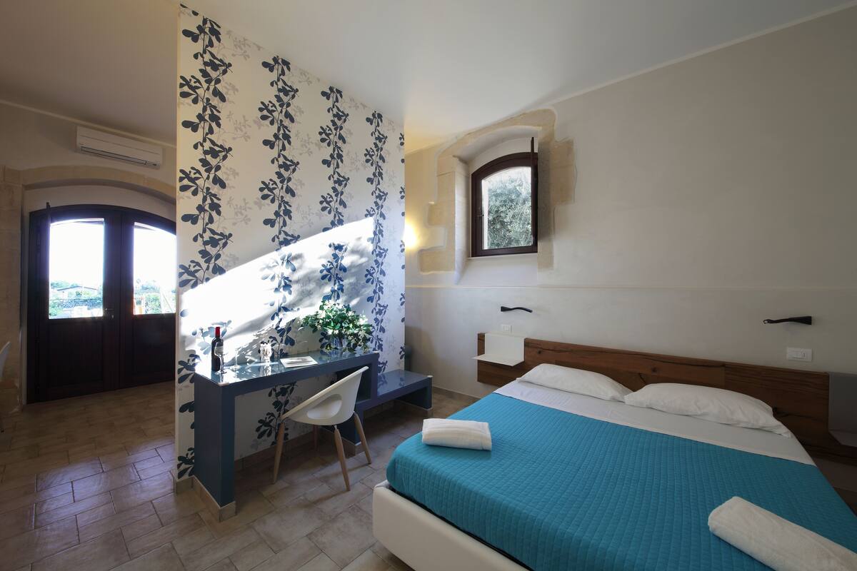 A bedroom with a bed, a desk, and a chair.