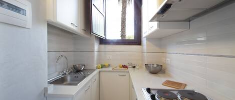 A compact kitchen with a sink, stove, and window.