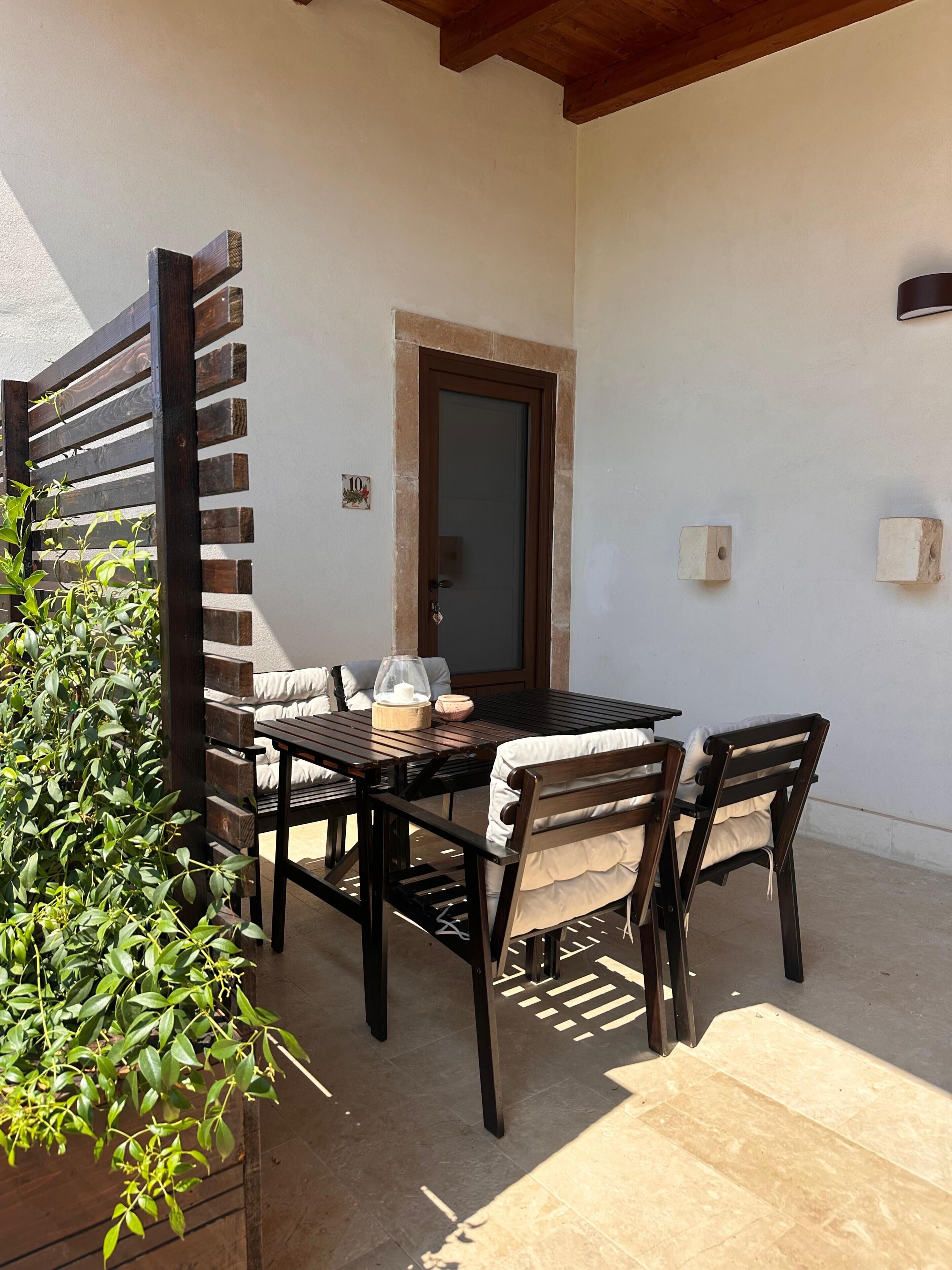 Une terrasse avec une table et des chaises, une clôture en bois et une porte.