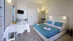 Un dormitorio con una cama, un escritorio, una silla y un televisor fijado a la pared.