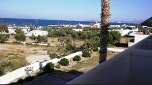 A coastal view with a palm tree, buildings, and the sea. - Christina Studios (Kos)
