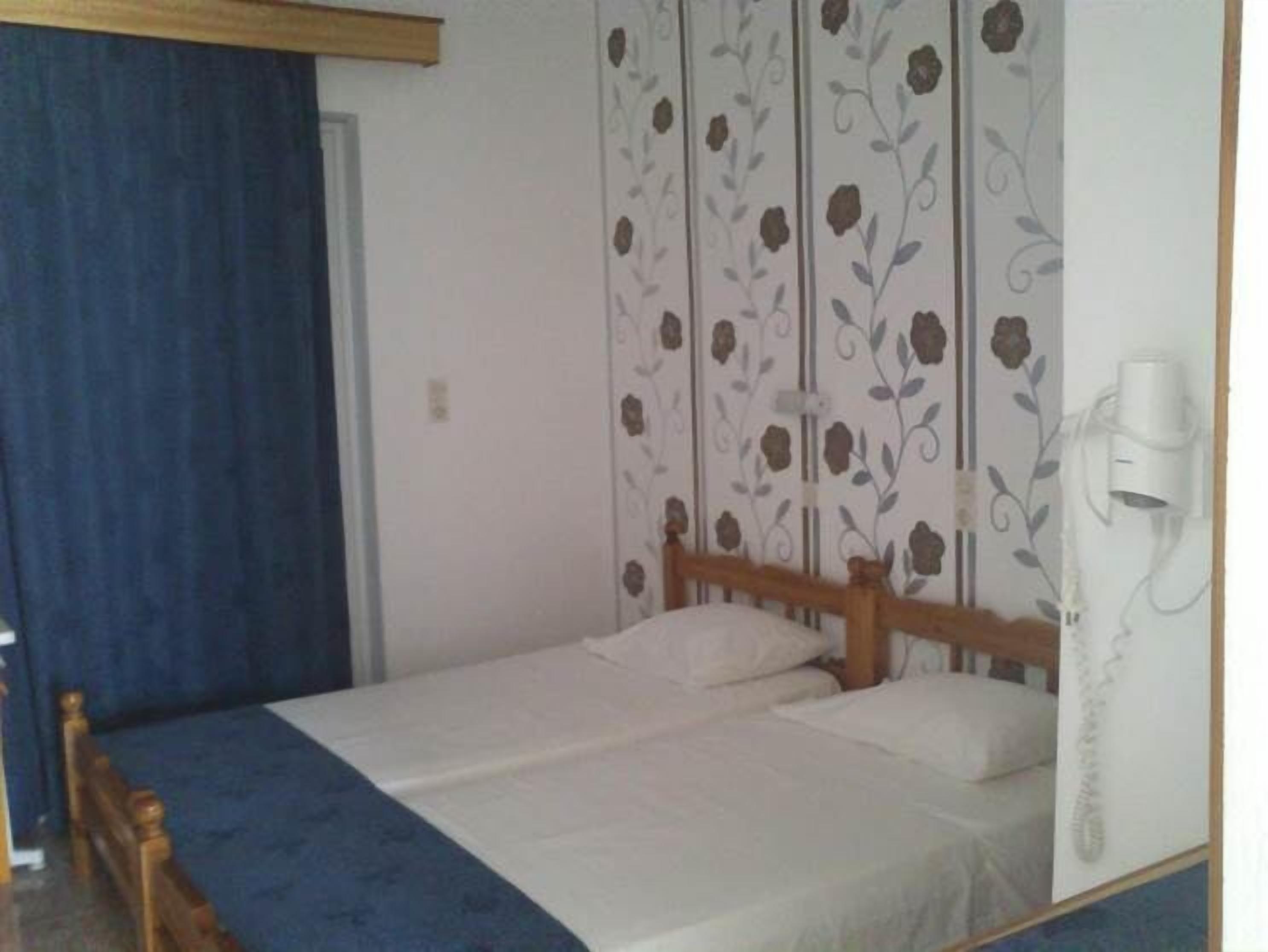 A bedroom with a bed, a wooden headboard, a blue curtain, and a floral-patterned wall.