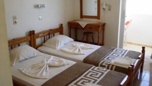 A hotel room with two wooden beds, a wooden desk, a mirror, and a small stool. - Christina Studios (Kos)