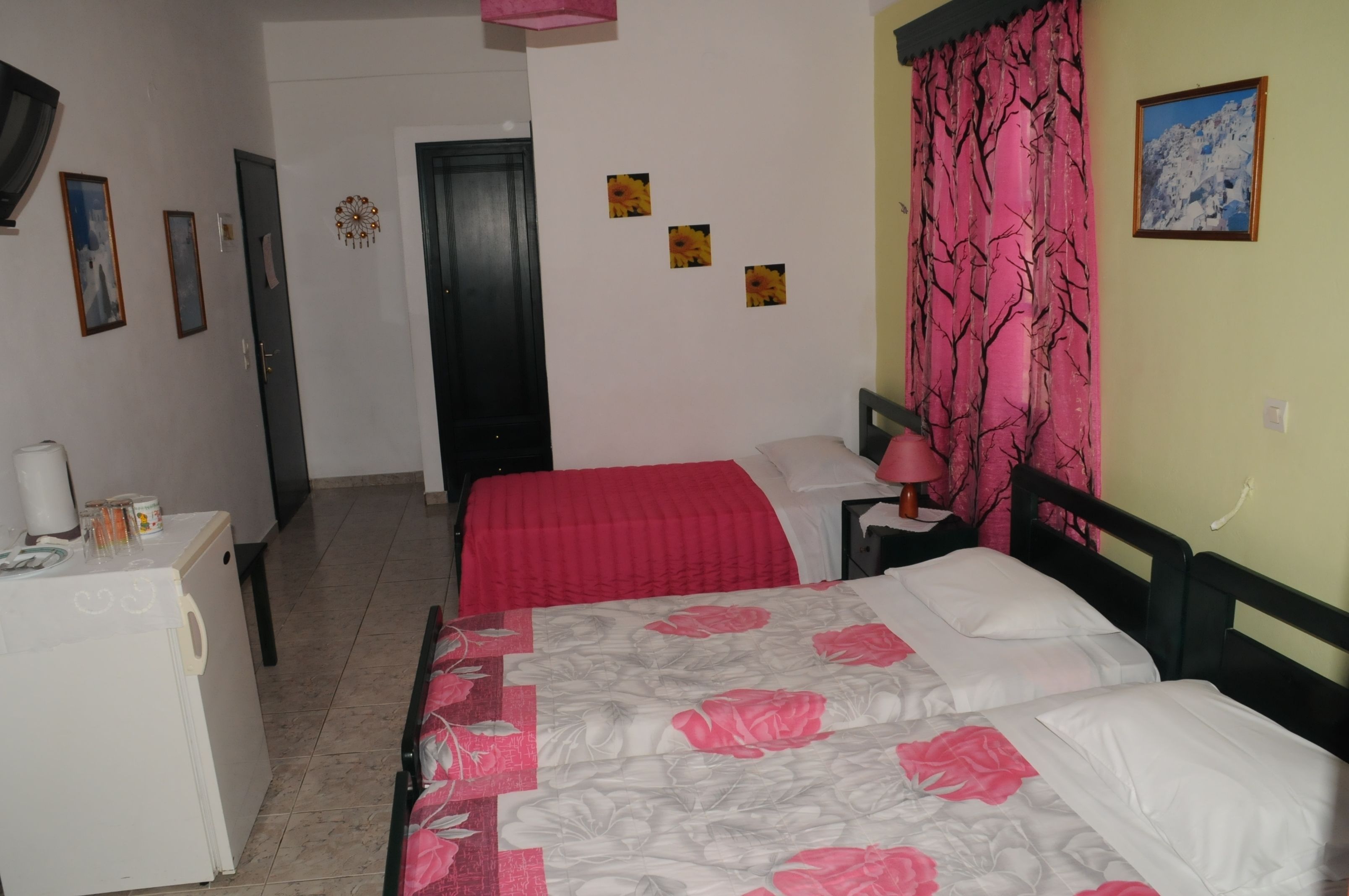 A bedroom with a bed, a nightstand, a desk, and a refrigerator.