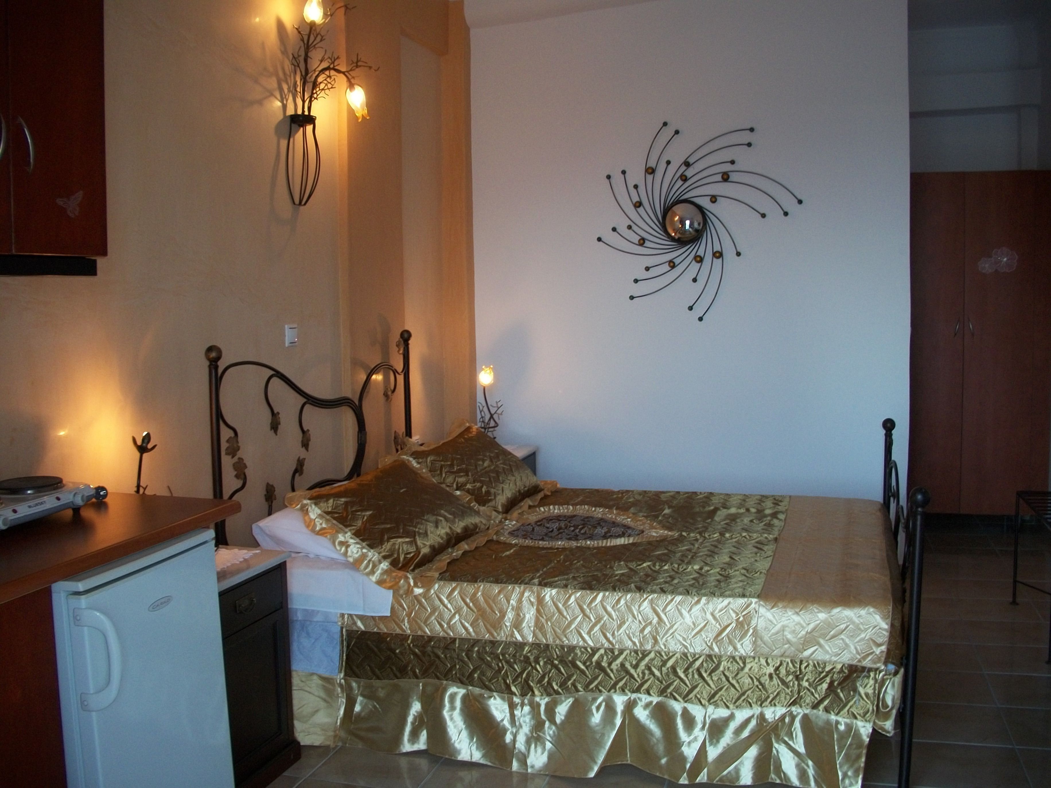 A bedroom with a bed, a nightstand, a wall-mounted lamp, and a decorative wall piece.