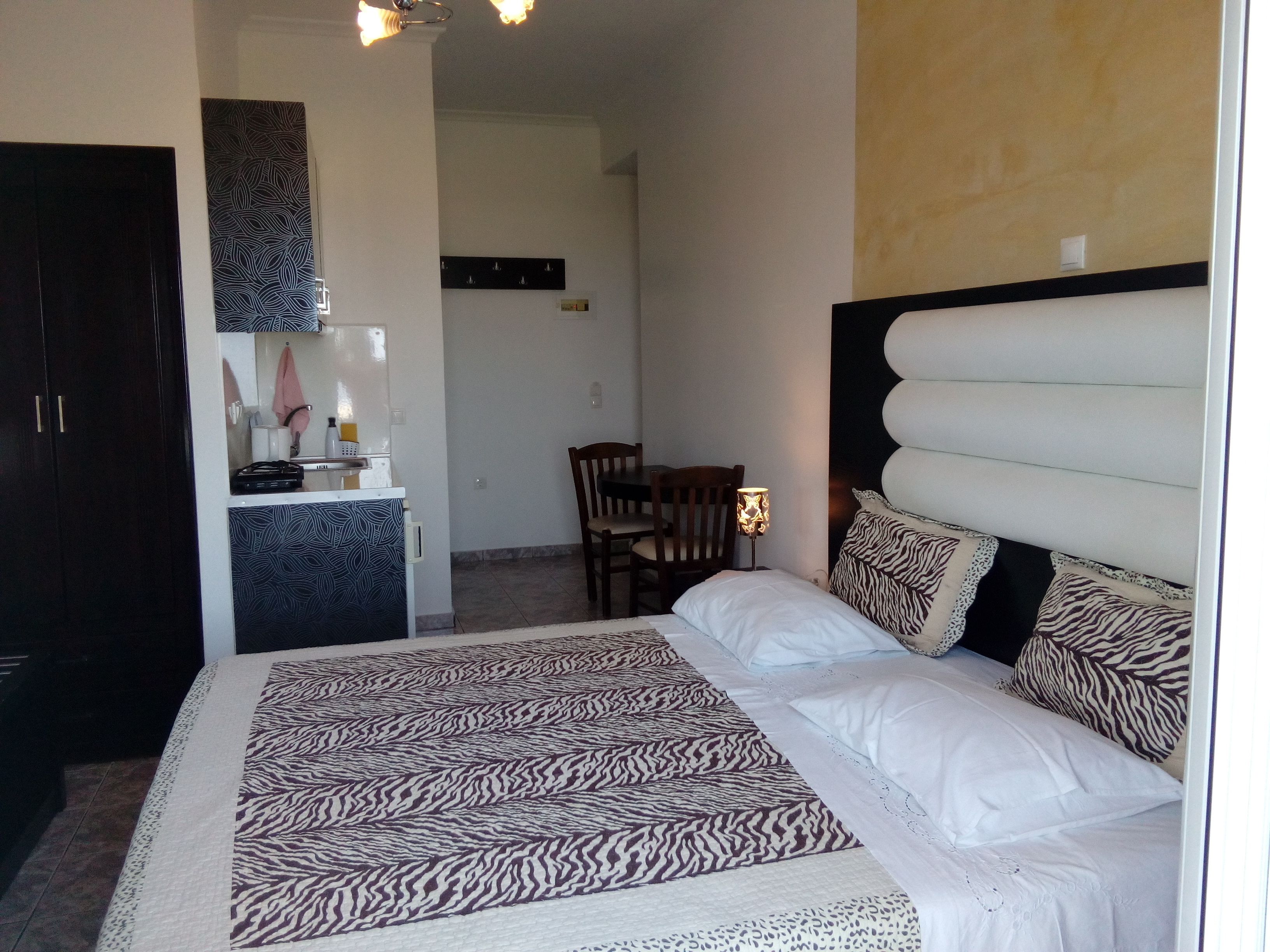 A bedroom with a bed, a desk with a chair, and a small dining area.