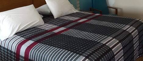 A hotel room with a bed, a nightstand, a lamp, and a wall with three framed pictures.