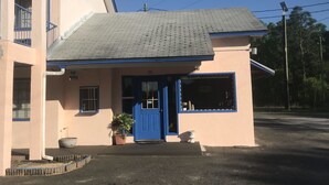 Un edificio con una porta e finestre blu, un piccolo portico con una pianta in vaso e un cartello che recita 'LPG FOR SERVICE'.