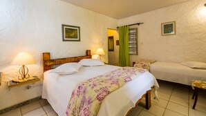 A hotel room with a large bed, a smaller bed, two bedside tables with lamps, and a green curtain. - Pousada Cesar (São Bento do Sapucaí)