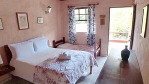 A bedroom with a large bed, a smaller bed, and a wooden table. - Pousada Cesar (São Bento do Sapucaí)