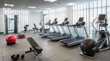 Ett gym med löpband, crosstrainers, en träningsbänk, hantlar och en röd träningsboll.