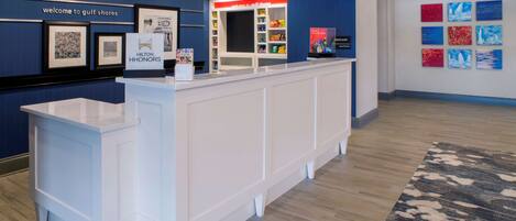 A reception area with a counter, framed pictures on the wall, and a 'Welcome to Gulf Shores' sign.