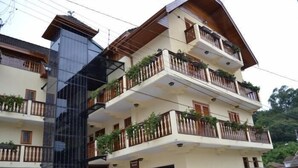 A multi-story building with balconies, a glass elevator shaft, and a sign indicating a restaurant. - Pousada Alemã (Santo Antonio do Pinhal)