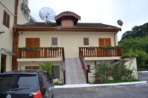 A two-story building with a balcony on the upper floor, a satellite dish on the roof, and a car parked in front. - Pousada Alemã (Santo Antonio do Pinhal)