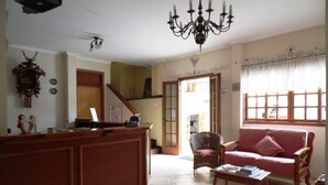 A living room with a sofa, a coffee table, a chandelier, and a wooden cabinet. - Pousada Alemã (Santo Antonio do Pinhal)