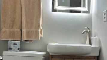 Un baño con inodoro, lavamanos, armario de madera y un toallero con varias toallas.