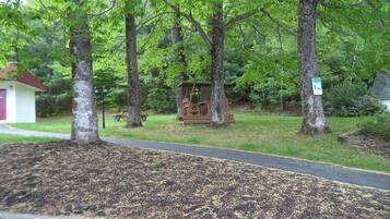A park with a swing set, a picnic table, and a small shed.