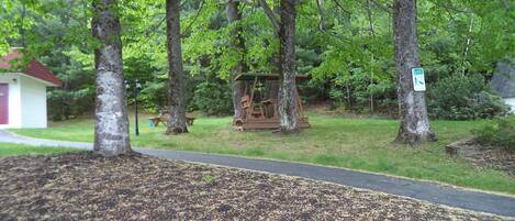A park with a swing set, a picnic table, and a small shed.