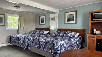 A hotel room with two beds, a wooden cabinet, a television, and framed pictures on the wall.
