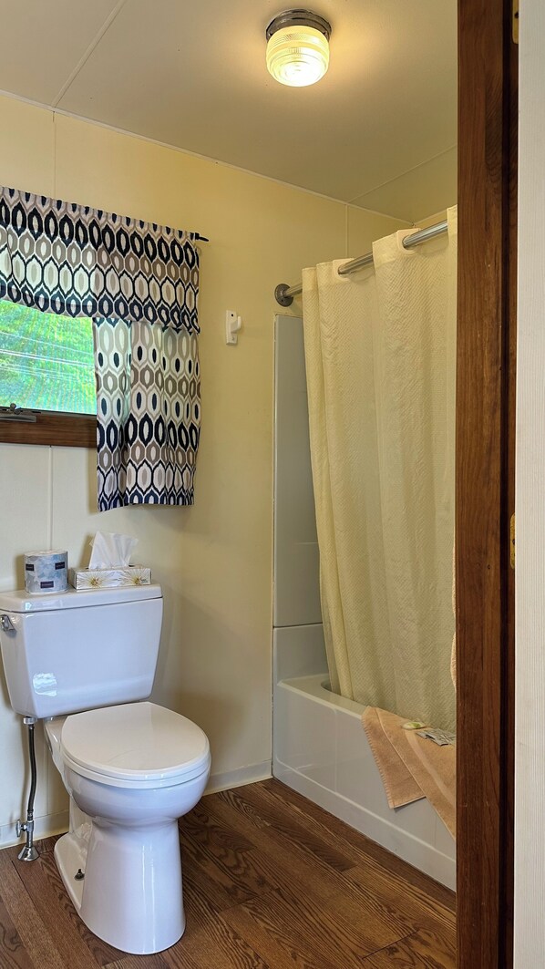 Un baño con inodoro, ducha con cortina y decoración de pared estampada.