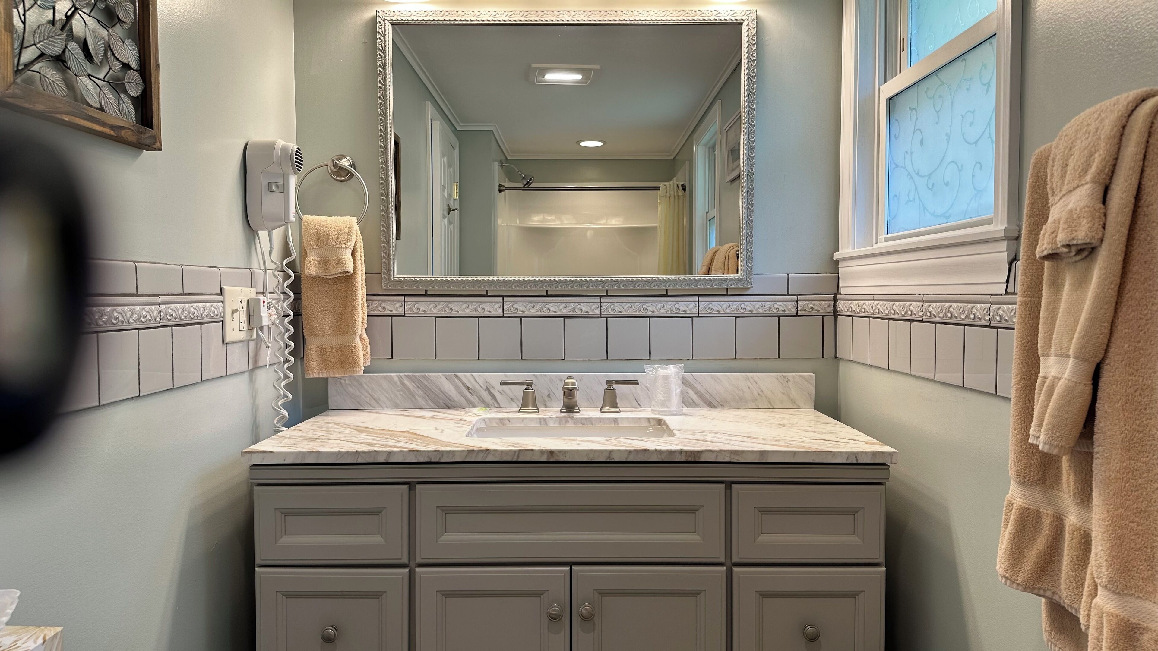 A bathroom with a marble sink, a large mirror, and a vanity with drawers.