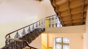 Un escalier orné de rampes en métal ouvragé et doté d’un plafond en bois.
