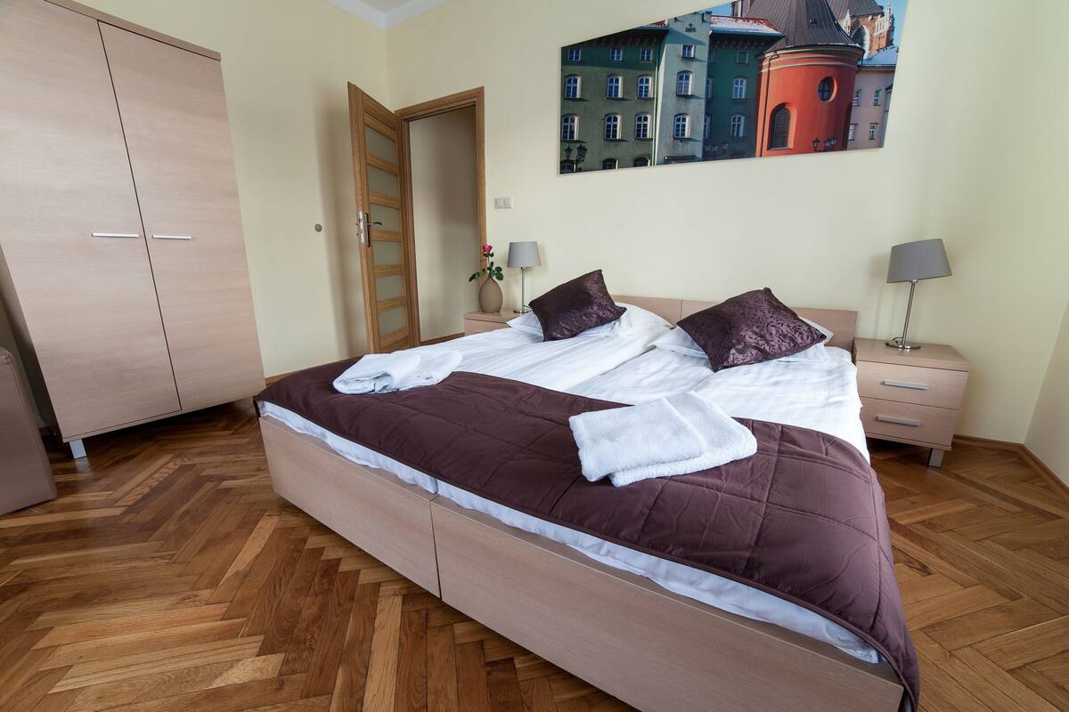 Ein Schlafzimmer mit Bett, Holzschrank, Nachttischen und einem Bild an der Wand.