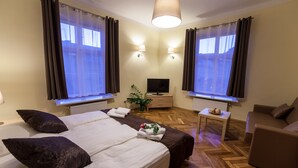 Une chambre d’hôtel avec un grand lit, une télévision, une petite table et un canapé.