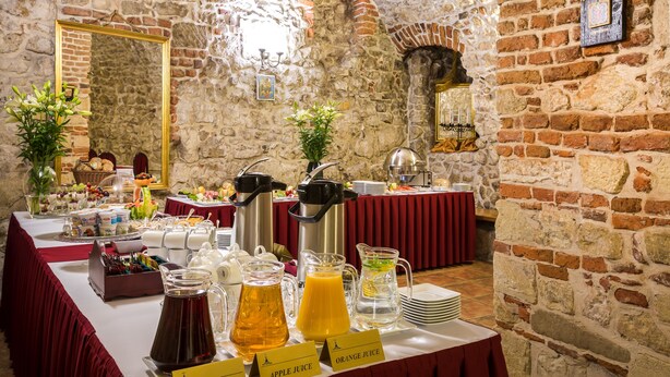 Un buffet de petit-déjeuner proposant une variété d’aliments et de boissons, le tout présenté sur fond de mur en pierre.