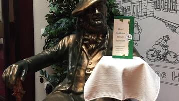 Eine Statue eines Mannes im Anzug mit einem grünen Schild auf einem Tisch davor.