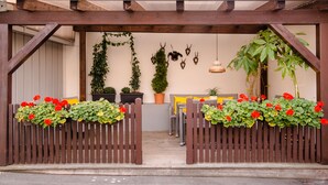 A wooden pergola entrance with potted plants and a seating area with cushions. - Hotel Goldener Hirsch (Bayreuth)