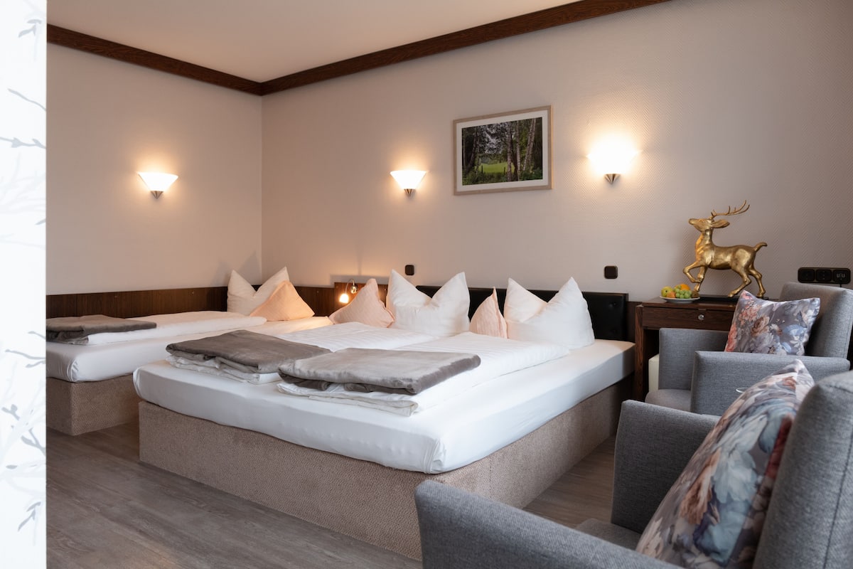 A modern bedroom with a large bed, two bedside tables, a nightstand, and a decorative deer statue.