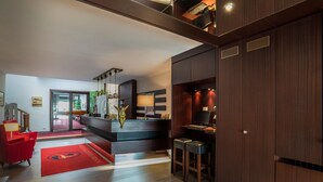 A modern hotel lobby with a reception desk, red seating area, and a large wooden wardrobe. - Hotel Goldener Hirsch (Bayreuth)