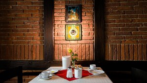 A dining table set with white tableware, a red placemat, and a vase with a single flower. - Hotel Goldener Hirsch (Bayreuth)