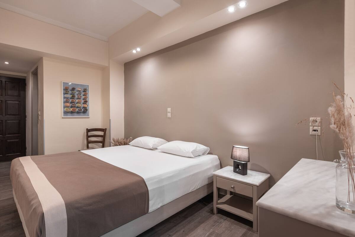 A modern bedroom with a bed, bedside table, lamp, and a wall-mounted artwork.