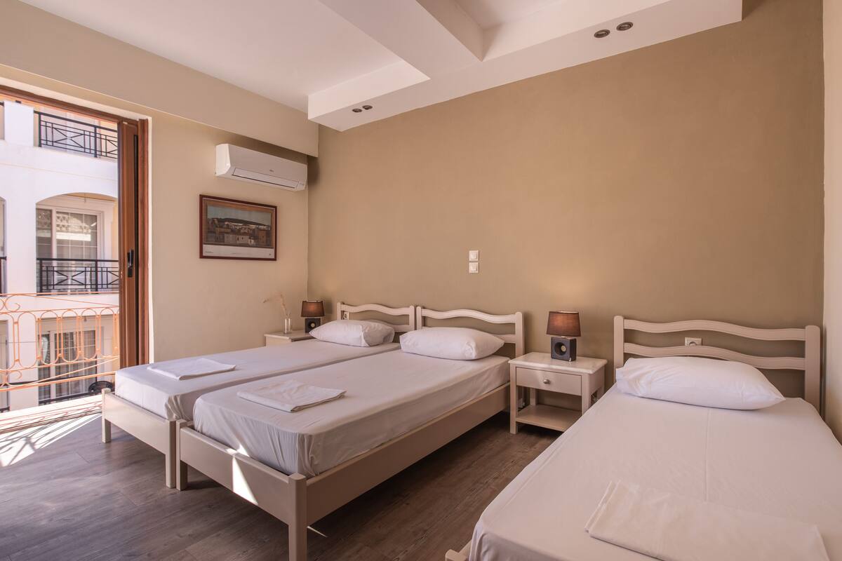 A hotel room with two beds, a balcony, and a painting on the wall.