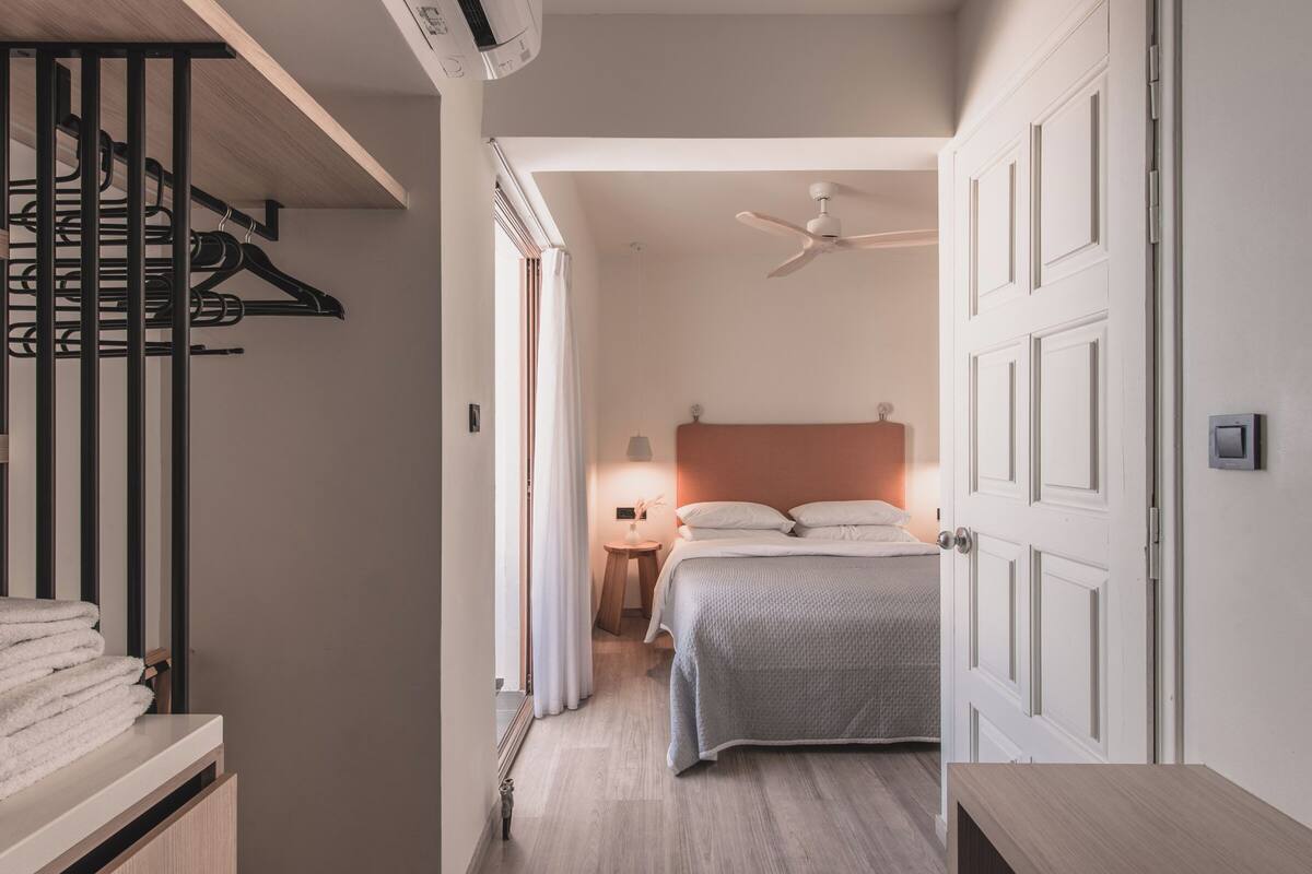 A bedroom with a bed, a nightstand, a ceiling fan, and a wardrobe.