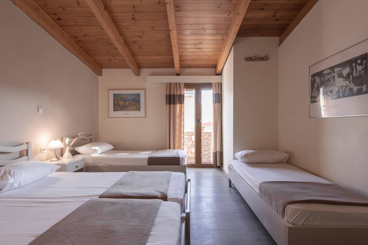 A room with two beds, a nightstand, a lamp, and a painting on the wall.
