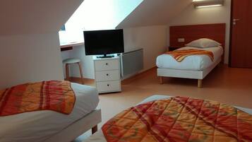 A bedroom with two beds, a TV, a desk, and a chair.