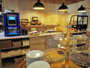 A buffet setup with various food items, a coffee machine, and a self-service beverage dispenser. - Beddy-Bye Hôtel (Contrexéville)