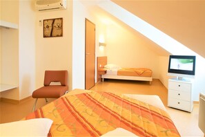 A bedroom with a bed, a chair, a TV, and a nightstand. - Beddy-Bye Hôtel (Contrexéville)