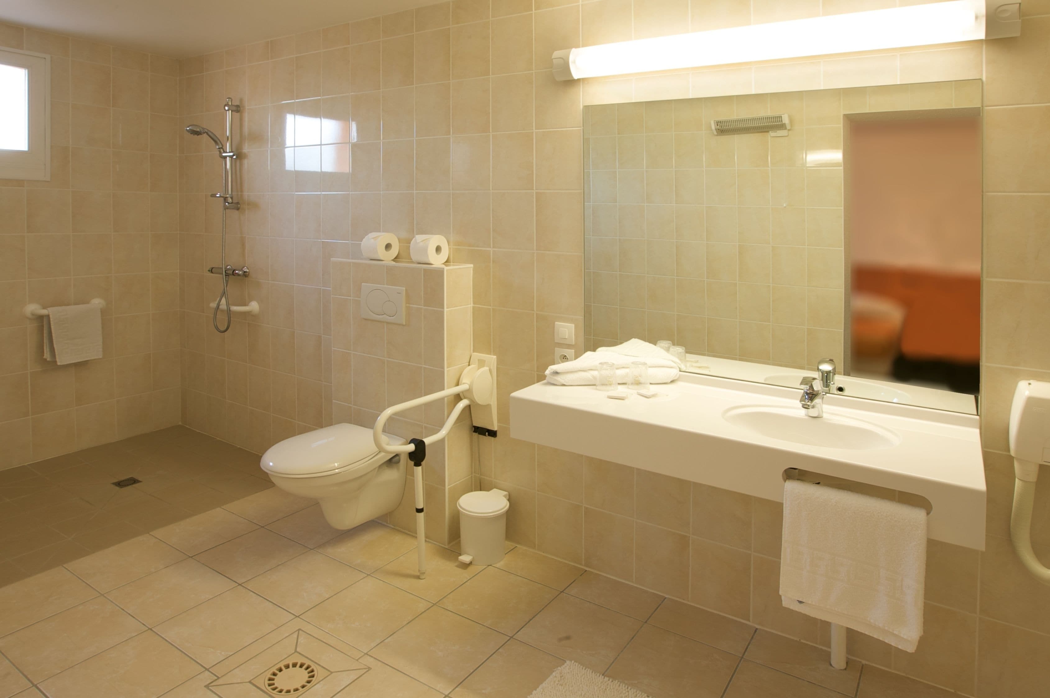 A modern bathroom with a toilet, bidet, sink, and mirror.