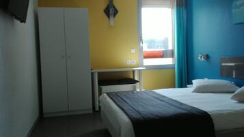 Ein Schlafzimmer mit Bett, Kleiderschrank, Schreibtisch und einem Fenster mit Vorhängen.