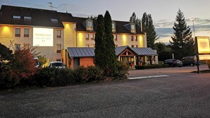A hotel with multiple buildings, a gravel driveway, and parked cars.