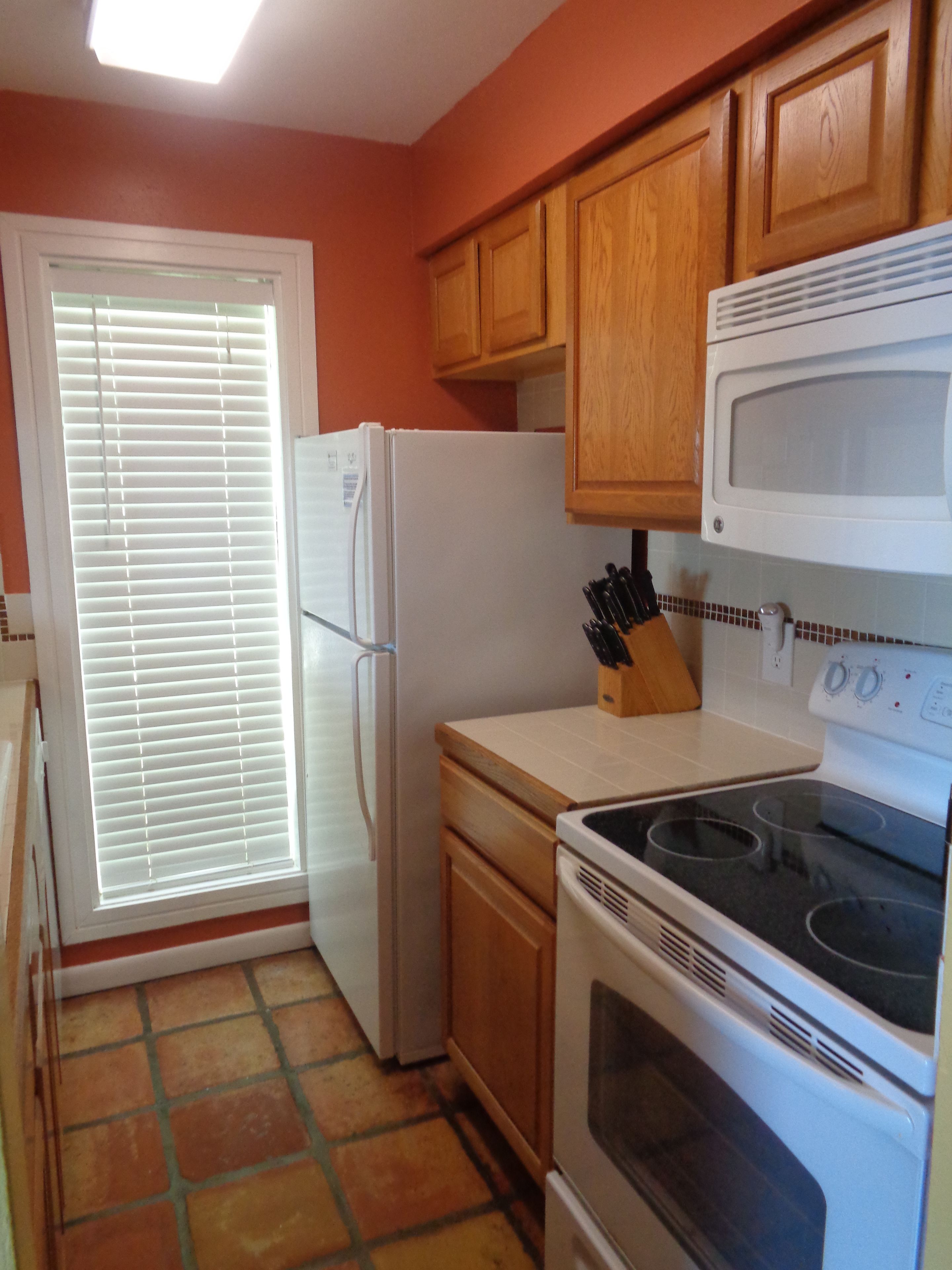 A kitchen with wooden cabinets, a white refrigerator, a stove, and a microwave.